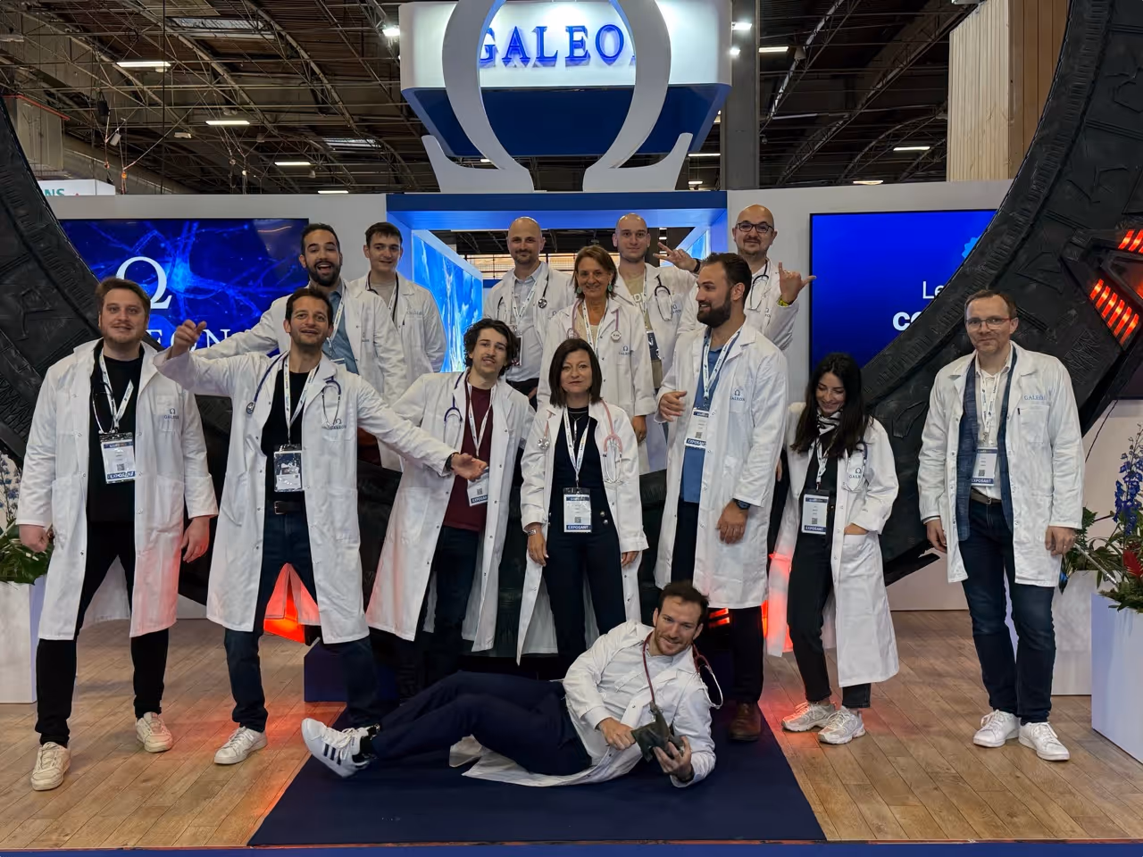 The Galeon team in white coats posing in front of their booth at a trade show